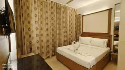 a hotel room with a bed with a towel on it at Hotel Roopa in Mysore
