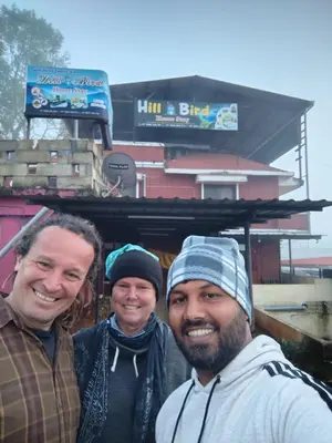 three men posing for a picture in front of a building at HILL BIRD HOME STAY Ooty in Ooty