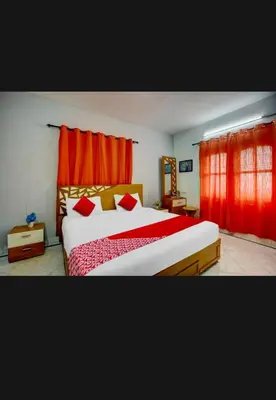 a bedroom with a large bed with red curtains at HILL BIRD HOME STAY Ooty in Ooty
