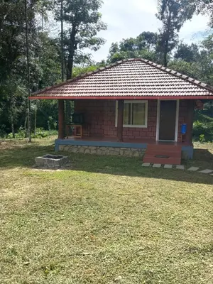 a small red brick house with a yard at Nature Spot Cottages Coorg in Kurchi