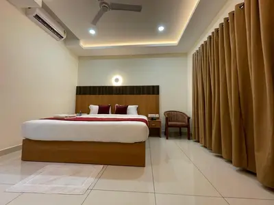 a bedroom with a large bed and a chair at Hotel Deepakam Inn in Palakkad