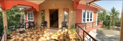 a home with a balcony with a staircase to a house at Coorg Stream Side Homestay in Ponnampet