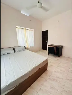 a bedroom with a large bed and a desk at Homestay Guruvayur, 2 AC Bedrooms, Hall, Veranda, Kitchen in Guruvāyūr