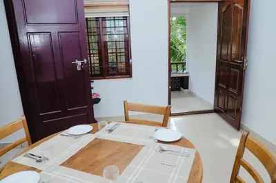 a dining room with a wooden table and chairs at Sankalpa Homestay in North Paravur
