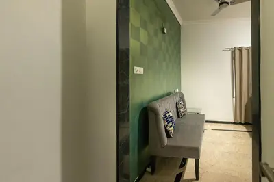 a room with a chair and a green wall at Hive Service Apartment in Coimbatore