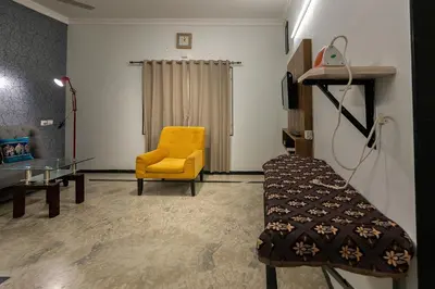 a living room with a yellow chair and a glass table at Hive Service Apartment in Coimbatore