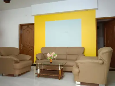 a living room with two chairs and a couch and a table at Savi's home stay in Ooty
