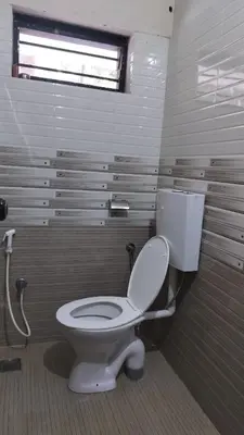 a bathroom with a white toilet and a window at Aptha Ayurveda in Kadikkād