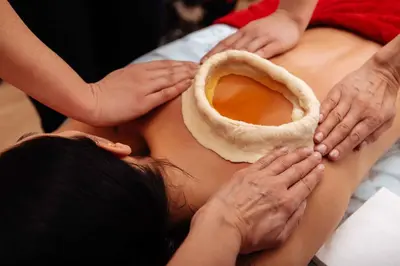 a woman is getting a massage with a piece of bread at Aptha Ayurveda in Kadikkād