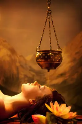 a woman laying on a table with a lamp hanging over her head at Aptha Ayurveda in Kadikkād