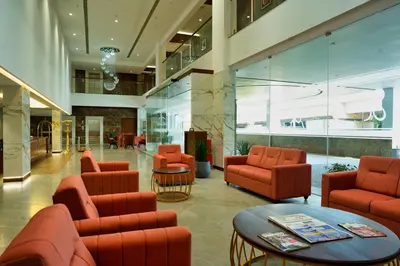 a lobby with orange chairs and a table at Gokulam Park Guruvayur in Guruvāyūr