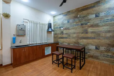 a kitchen with a wooden wall with a table and stools at MUGUNDAN 'S SMART STAY in Coimbatore