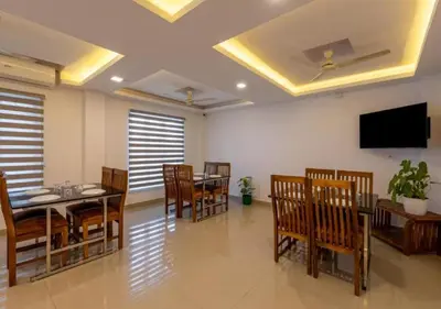 a dining room with tables and chairs and a flat screen tv at Airport Avenue Plaza in Nedumbassery