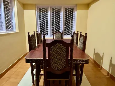 a dining room table with chairs and a window at Kokaris Coorg Homestay in Kushālnagar
