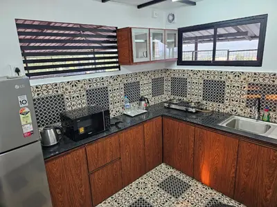 a kitchen with wooden cabinets and a sink and a refrigerator at Hamsted in Kottakkal
