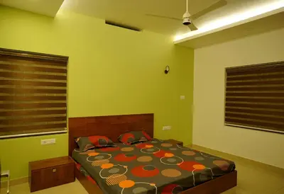 a bedroom with a bed in a room with green walls at Homestay- Near to Cochin Airport in Kāladi