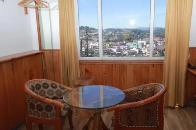 a glass table and chairs in a room with windows at The Woodlands Residency- Unmarried and stag groups not allowed in Ooty