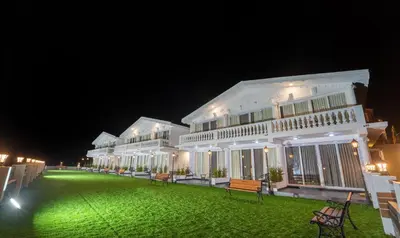 a large white building with a green yard at night at Treebo Skydale Premium Suites, 1500 Mtrs From Ooty Lake in Ooty