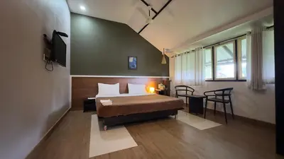 a bedroom with a bed and a table and chairs at Western Ghats Holiday Home in Kalpetta