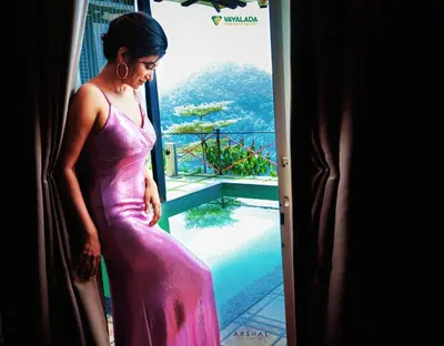 a woman in a pink dress looking out a window at Vayalada View Point Resort in Kozhikode