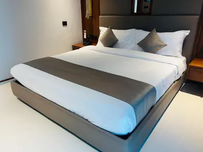 a large bed with white sheets and pillows at Hotel Bluebell in Kozhikode