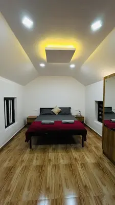a bedroom with a bed in a room with wooden floors at Aadhya Homestay 4BHK in Wayanad
