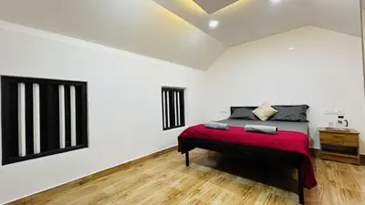 a bedroom with a bed with a red blanket at Aadhya Homestay 4BHK in Wayanad