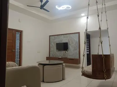 a living room with a couch and a table and a tv at Thulasi Avenue Inn in Pollāchi