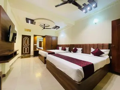 a bedroom with two beds and a flat screen tv at Hotel Boss Palace in Mysore