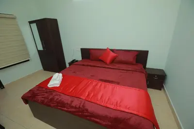 a red bed with red pillows in a bedroom at Premier Tourist Home in Kunnamkulam
