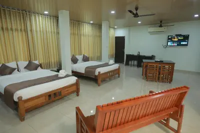 a bedroom with two beds and a television in it at Premier Tourist Home in Kunnamkulam