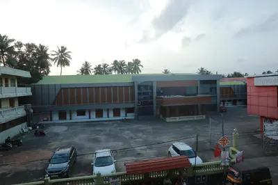 a parking lot with cars parked in front of a building at Premier Tourist Home in Kunnamkulam