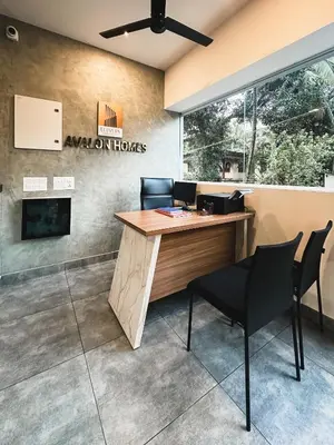 an office with a desk and chairs and a sign at Avalon Homes in Perintalmanna