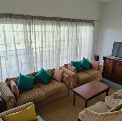 a living room with two couches and a tv at Tranquil Haven Kotagiri in Kotagiri