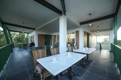 a dining room with tables and chairs on a balcony at Tranquil Haven Kotagiri in Kotagiri