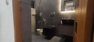 a bathroom with a black toilet and a sink at Mountain View Villa in Mukkam