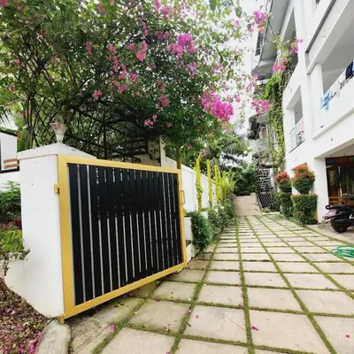 a gate on a sidewalk next to a building with pink flowers at UPPU HOMESTAY in Mulappilangād