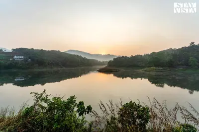 a river with the sun setting in the distance at StayVista at Lagoons Villa with Lawn, Pool, WiFi in Kozhikode