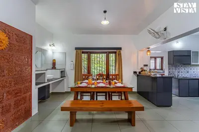 a kitchen with a table in the middle of a room at StayVista at Lagoons Villa with Lawn, Pool, WiFi in Kozhikode