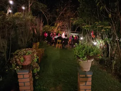 a group of people sitting at a table in a garden at night at Silver Spruce Glass Villa 1BHK Kotagiri in Kotagiri