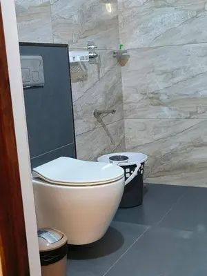 a bathroom with a toilet and a stone wall at Ananda Holiday Home in Ambalavayal