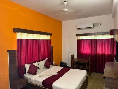a bedroom with a bed with red curtains and a desk at Hotel New Cresent park in Coimbatore