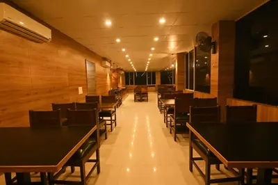 a dining room with black tables and chairs at THE DAWN HOTEL in Mysore