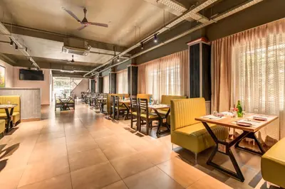 a dining room with tables and yellow chairs at Hotel Hari Govindas Mysore - Explore the Heart of Mysore in Mysore