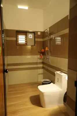 a bathroom with a toilet and a glass wall at Le Serene in Meenangadi