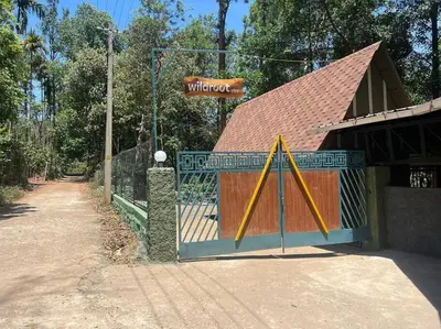 a gate with a sign in front of a building at Wildrootstay 3 bed cottage in Pinangode