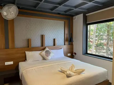a bedroom with a bed with a flower on it at Wildrootstay 3 bed cottage in Pinangode