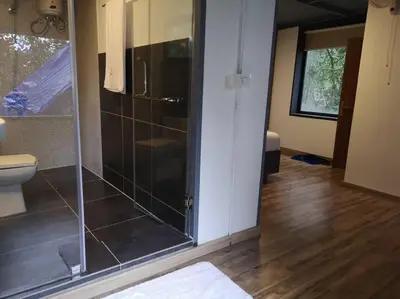 a bathroom with a glass shower and a toilet at Wildrootstay 3 bed cottage in Pinangode