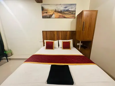 a bedroom with a bed with white sheets and red pillows at Rio Rooms Calicut Near Mims Hospital in Kozhikode