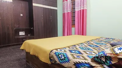 a bedroom with a bed with a yellow blanket on it at AR premium family homestay in Mysore